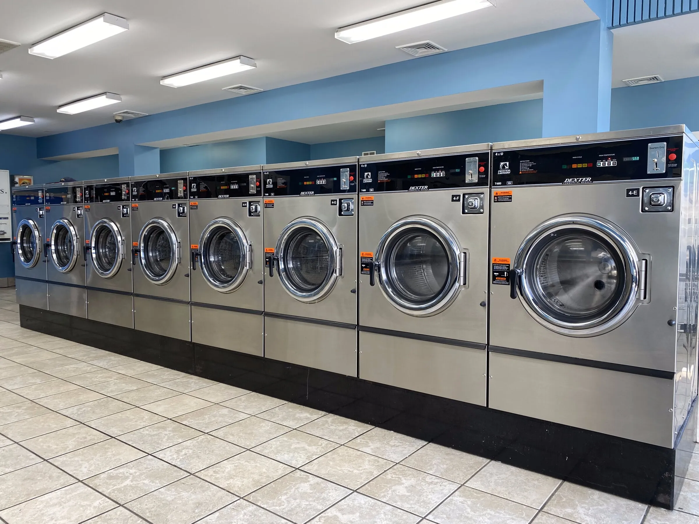 Eight large front-load washers in a row on a clean tile floor.